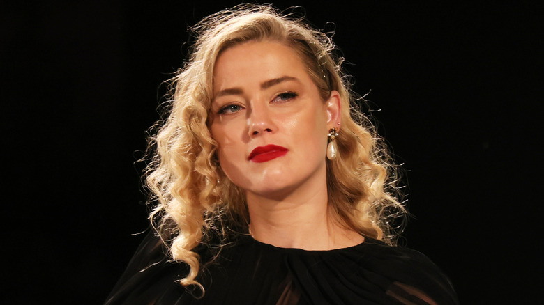 Amber entendu dans une robe noire devant le fond noir