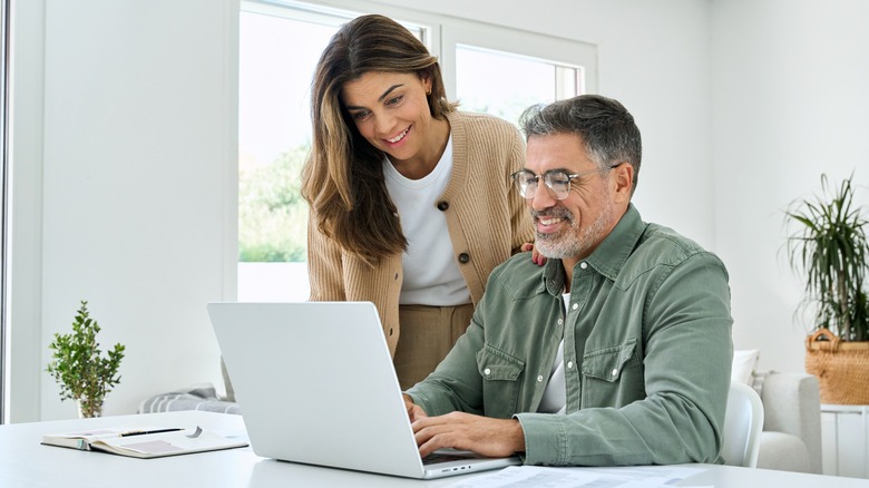 Couple regardant l'ordinateur et souriant