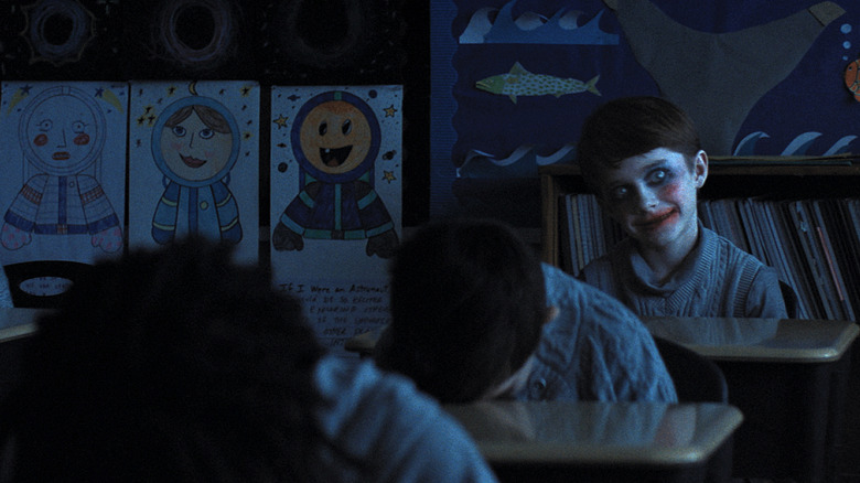 Un enfant spectral se longe de l'arrière de la classe