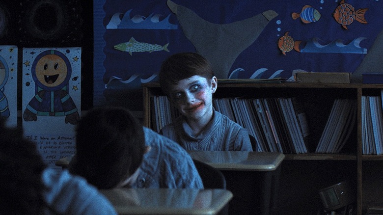 Alex souriant effrayant avec du maquillage de clown dans la salle de classe dans les armes