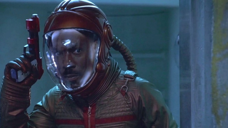 Pluton dans une combinaison spatiale tenant un pistolet 