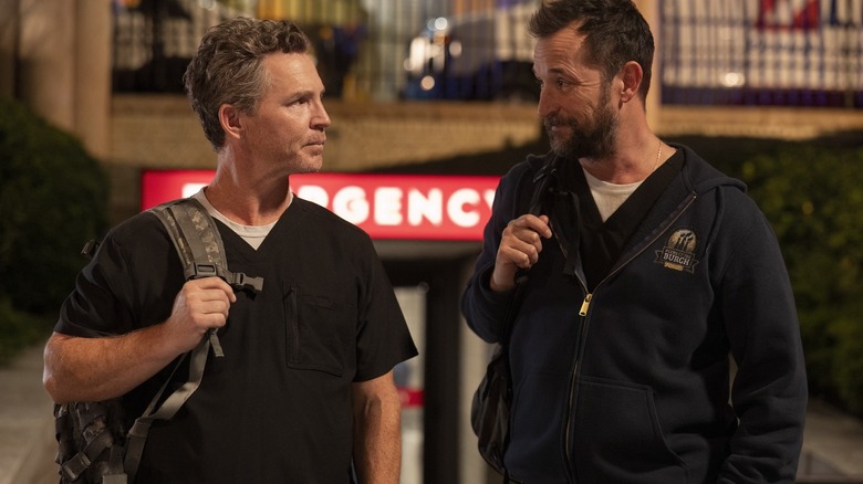 Le Dr Abbot et le Dr Robinavitch portant des sacs à dos tout en parlant dans 