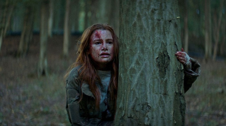 Maya Bloodied se cachant derrière un arbre (2025)