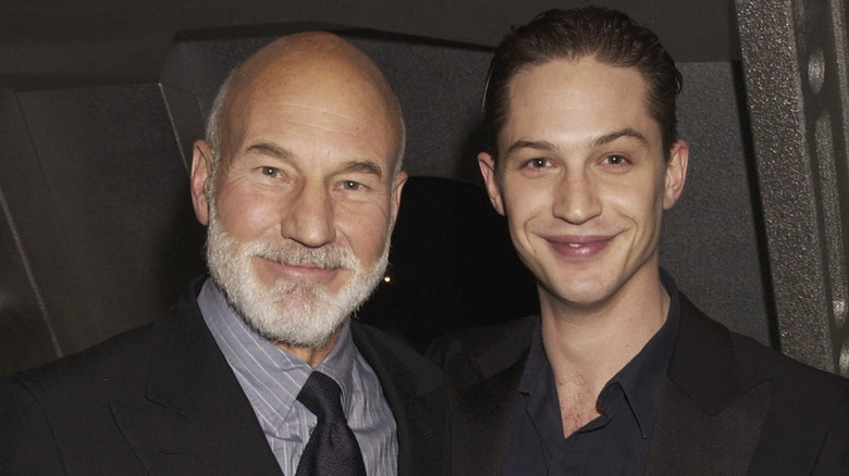 Patrick Stewart et Tom Hardy portant des costumes et souriant