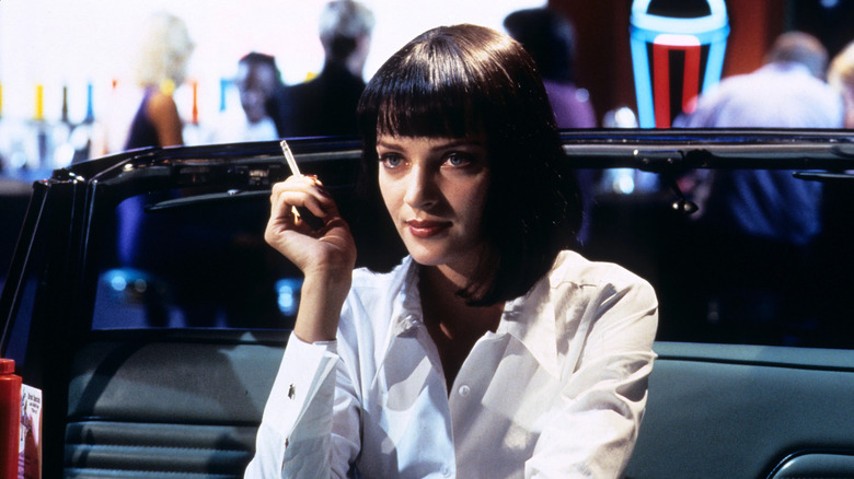 Mia Wallace assise dans son stand de voiture qui fume une cigarette en fiction à pâte