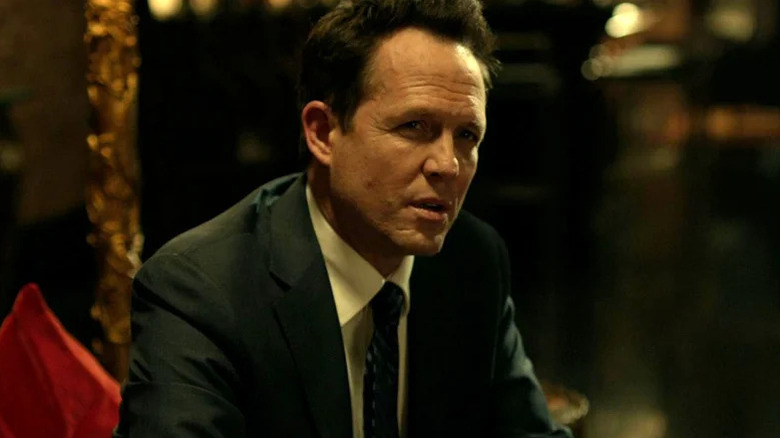 Avi, portant un costume, parle dans l'original John Wick.