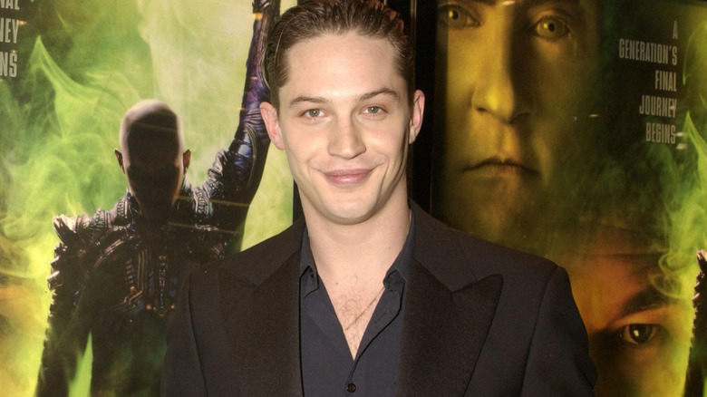 Tom Hardy debout devant les affiches pour Star Trek: Nemesis