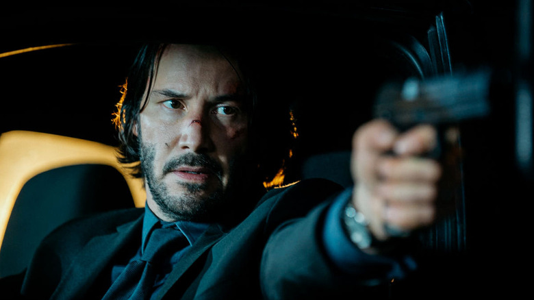 John Wick viant une arme à feu alors qu'il était assis dans une voiture