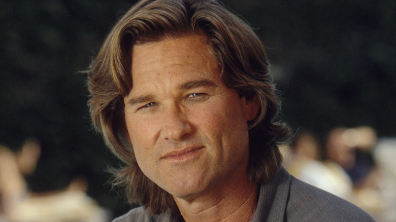 Kurt Russell assis dehors et souriant