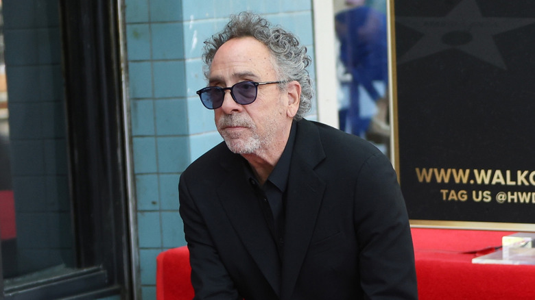 Tim Burton à genoux lors d'un événement sur le tapis rouge