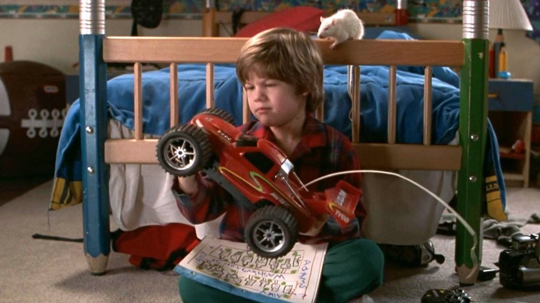 Alex tient une petite voiture tandis que son rat de compagnie est assis derrière lui dans Home Alone 3 (1997)