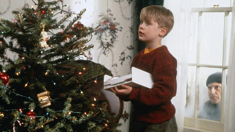 Kevin décorant l'arbre pendant qu'Harry regarde par la fenêtre dans Home Alone (1990)