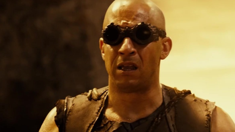 Riddick porte des lunettes et grimace dans Riddick (2013)