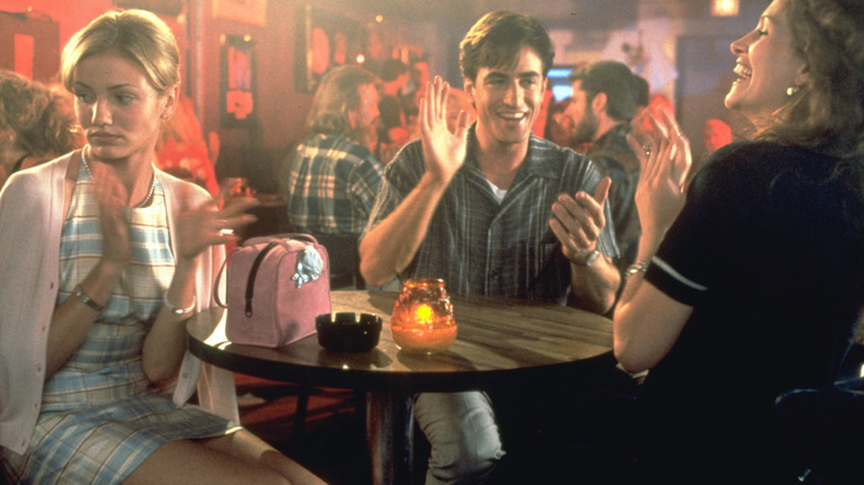 Kimmy, Michael et Julianne assis à une petite table ronde et applaudissant un artiste de karaoké hors caméra