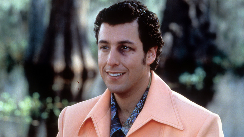 Bobby Boucher debout dans une veste de sport orange pastel et souriant malgré son oeil au beurre noir