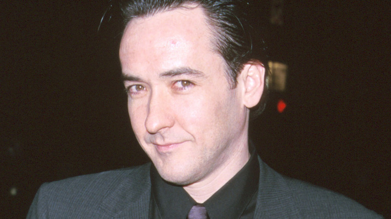 John Cusack souriant en costume