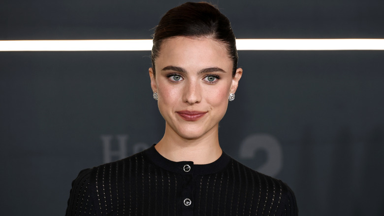 Margaret Qualley souriante dans un pull noir