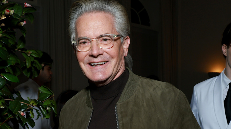 Kyle MacLachlan souriant dans une veste verte