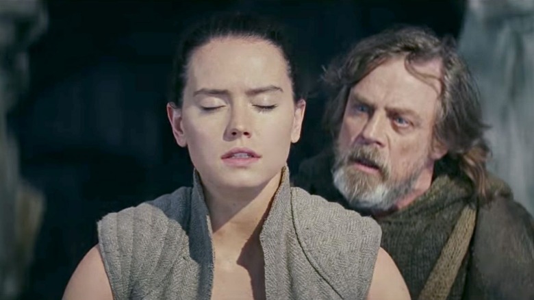 Rey ferme les yeux tandis que Luke Skywalker la guide à travers un exercice de méditation sur la Force. 