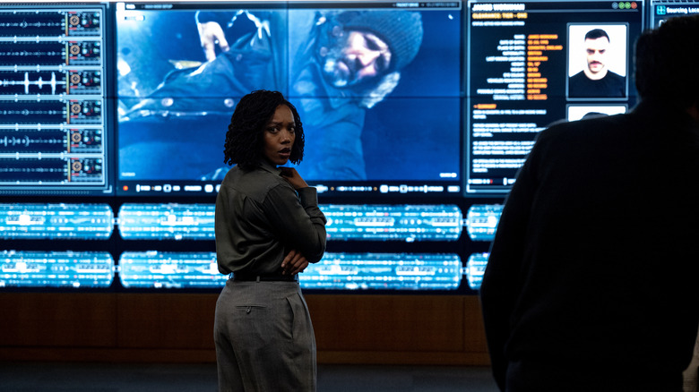 Roberta Frost se retourne devant des écrans géants