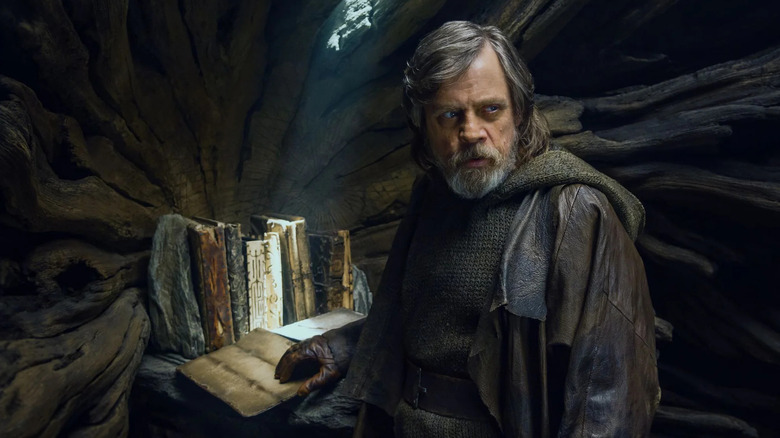 Luke Skywalker porte des vêtements marron sales alors qu'il se tient à l'intérieur d'un arbre contenant les anciens textes Jedi.