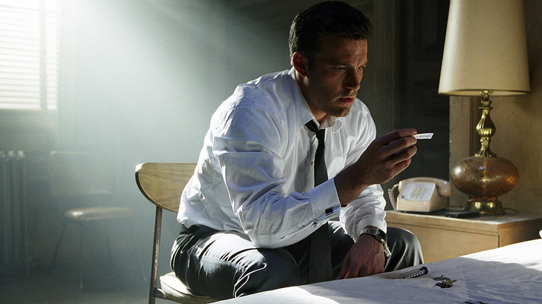 Jennings porte une chemise blanche et une cravate tout en tenant un message de fortune cookie