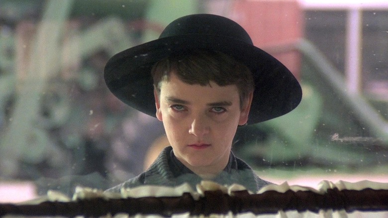 Enfant effrayant avec un chapeau noir regardant par la fenêtre dans Children of the Corn