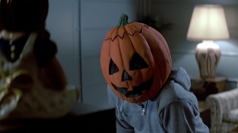 Un enfant vêtu d'un sweat à capuche bleu et portant un masque de citrouille regarde la télévision dans Halloween III : La Saison de la Sorcière