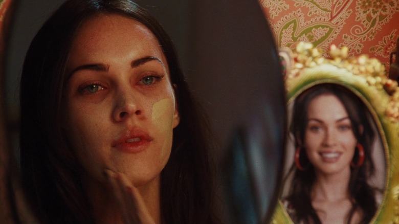 Jennifer Check appliquant du fond de teint dans le miroir à côté d'une photo dans Jennifer's Body