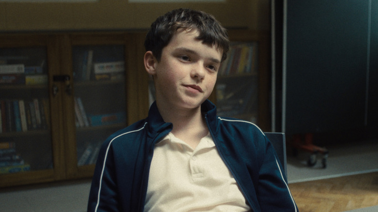 Jamie assis à une table, souriant, 