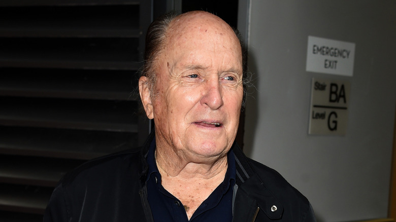 Robert Duvall debout près d’un panneau de sortie de secours