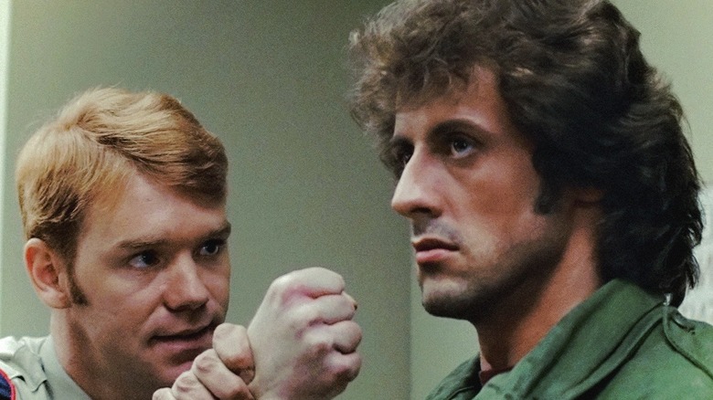 Rambo tenant l'adjoint Mitch par le poignet dans First Blood (1982)