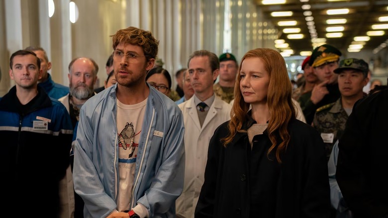 Grace debout à côté de Stratt et d'autres scientifiques du projet Hail Mary