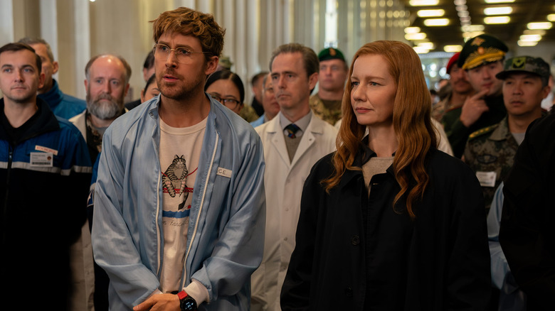 Ryland et Eva debout ensemble devant la foule dans le cadre du projet Hail Mary