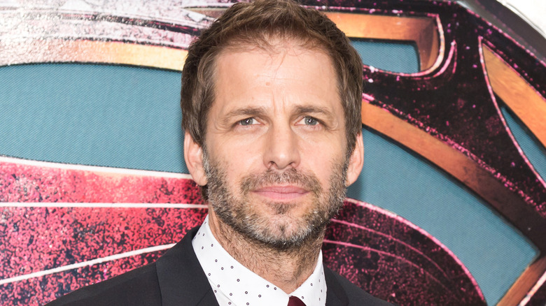 Zack Snyder posant devant un logo de Superman lors de la première de Man of Steel