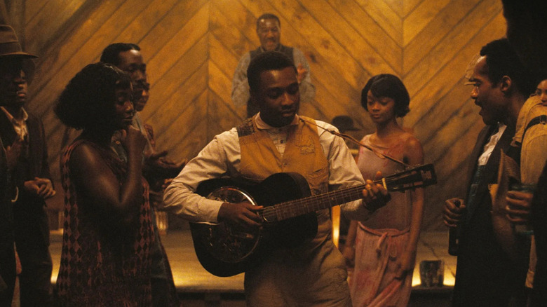 Sammy joue de sa guitare au juke joint dans Sinners