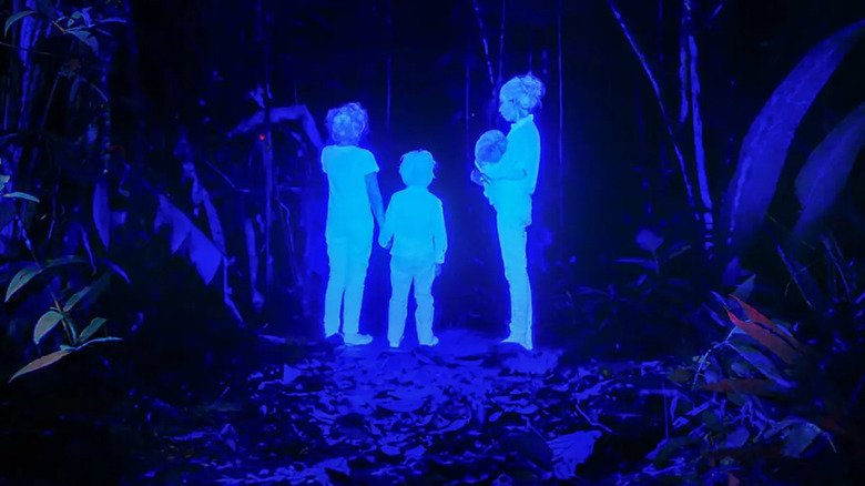 Quatre enfants brillants en bleu dans une forêt sombre 