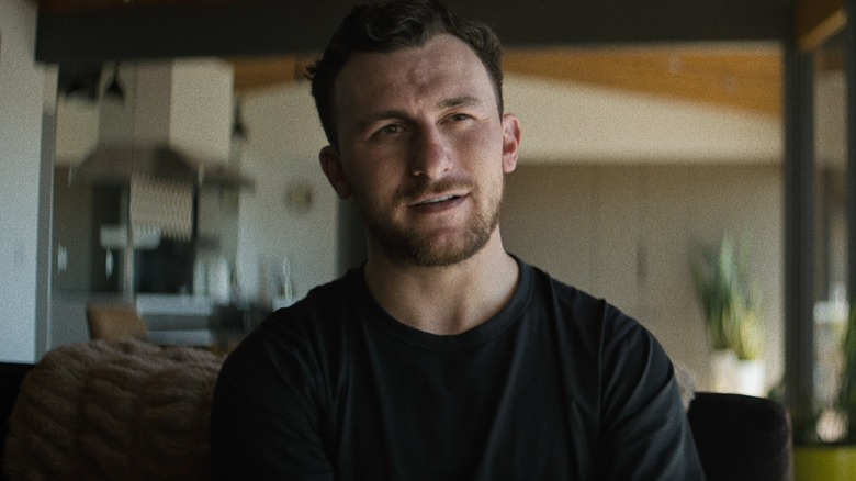 Johnny Manziel assis dans une maison avec un t-shirt noir dans Untold: Johnny Football (2023)