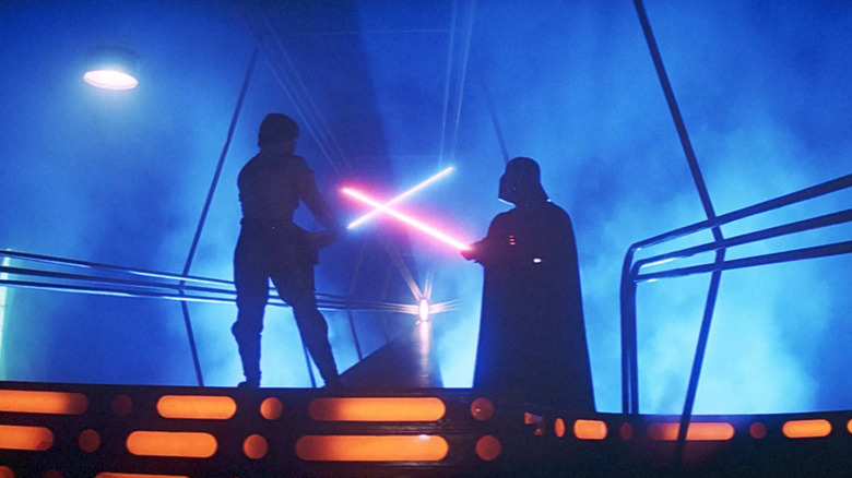 Luke Skywalker tient un sabre laser bleu lors d'un duel contre Dark Vador et son sabre laser rouge 