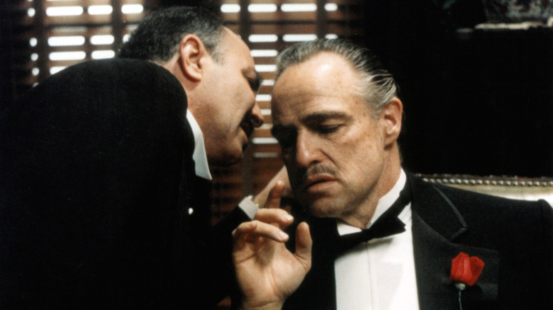Vito Corleone se fait murmurer quelque chose dans Le Parrain (1972)