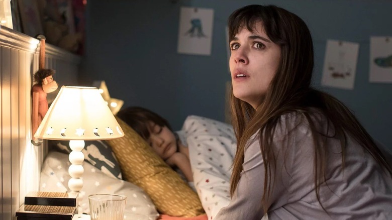 Vera assise à côté de son enfant dans son lit 