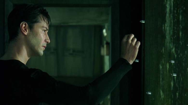 Neo tend la main vers les balles suspendues dans les airs dans The Matrix