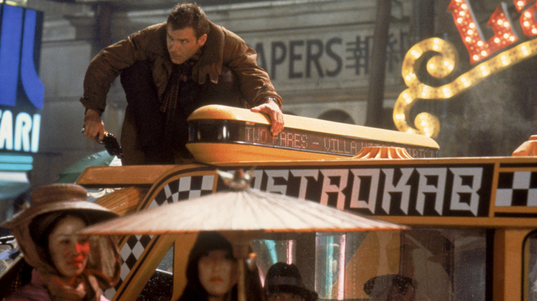 Decker accroupi au sommet d'un taxi dans Blade Runner (1982)