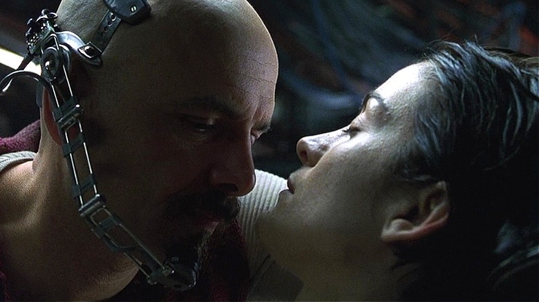 Cypher se penche près d'une Trinité inconsciente dans The Matrix