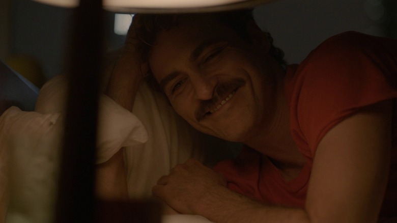 Theodore Twombly dans Her, souriant au lit la nuit en regardant sa table de nuit