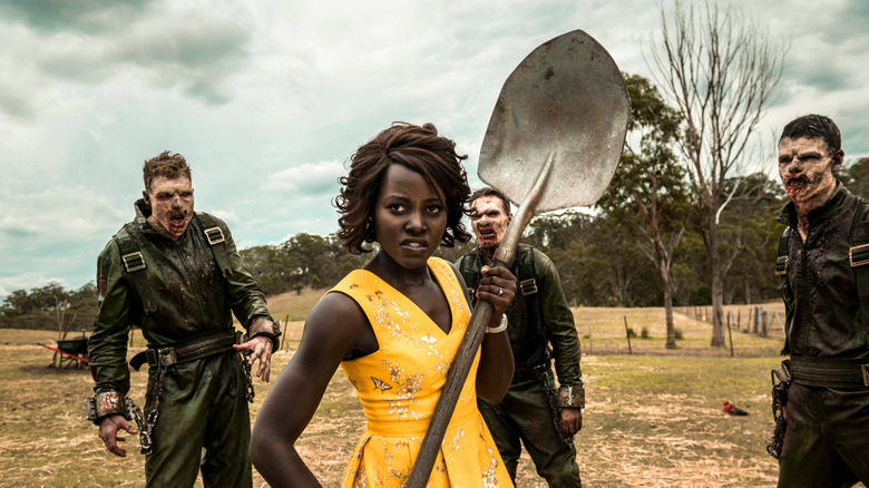 Miss Caroline brandit une pelle alors que les zombies s'approchent d'elle. 