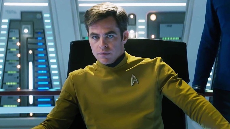 Le capitaine Kirk porte un uniforme jaune de Starfleet alors qu'il est assis dans un fauteuil de capitaine.