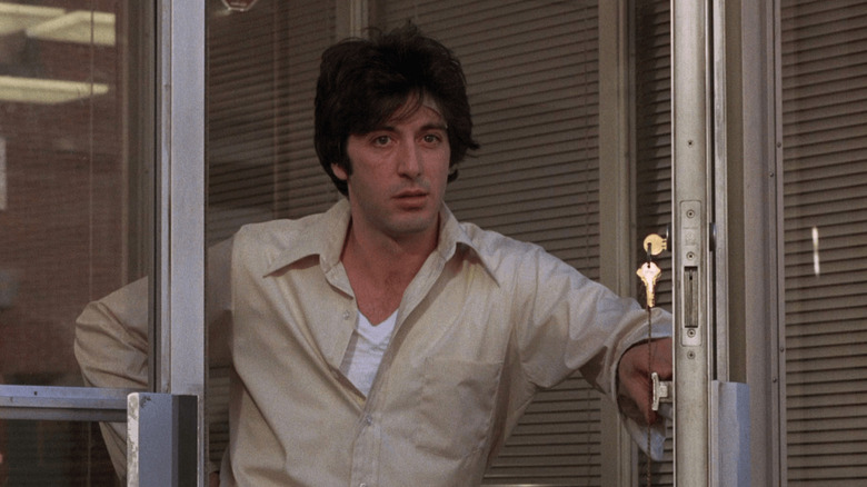 Sonny Wortzik porte une chemise blanche boutonnée tout en maintenant ouvertes les portes de la banque.