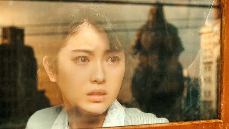 Noriko Oishi regardant Godzilla à travers une fenêtre (2023)