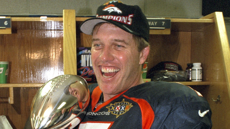 John Elway souriant et tenant le trophée Vince Lombardi